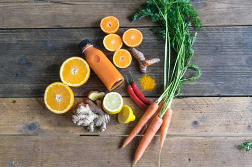 Image shows various fruits and vegetables and a bottle of fruit juice.